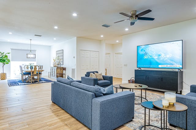 The living room boasts comfortable couches with a large 72 inch smart TV for stress-free relaxing