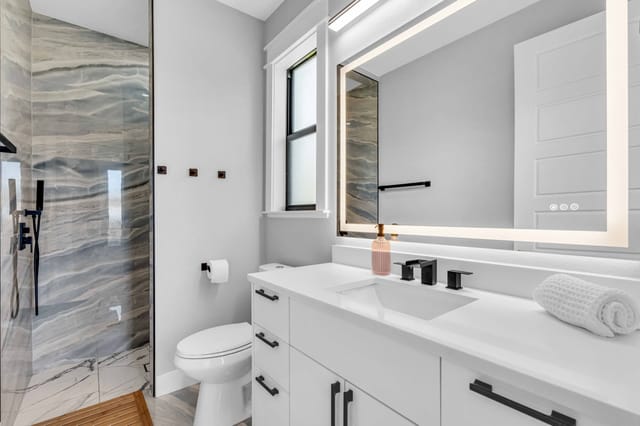 Luxuriously tiled bathroom with mirror lighting for your morning needs.