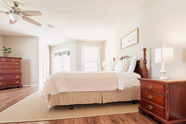 Coastal-inspired master suite with French doors to the screened pool deck
